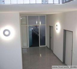 Eingangsfoyer mit Glastür und runden Wandleuchten